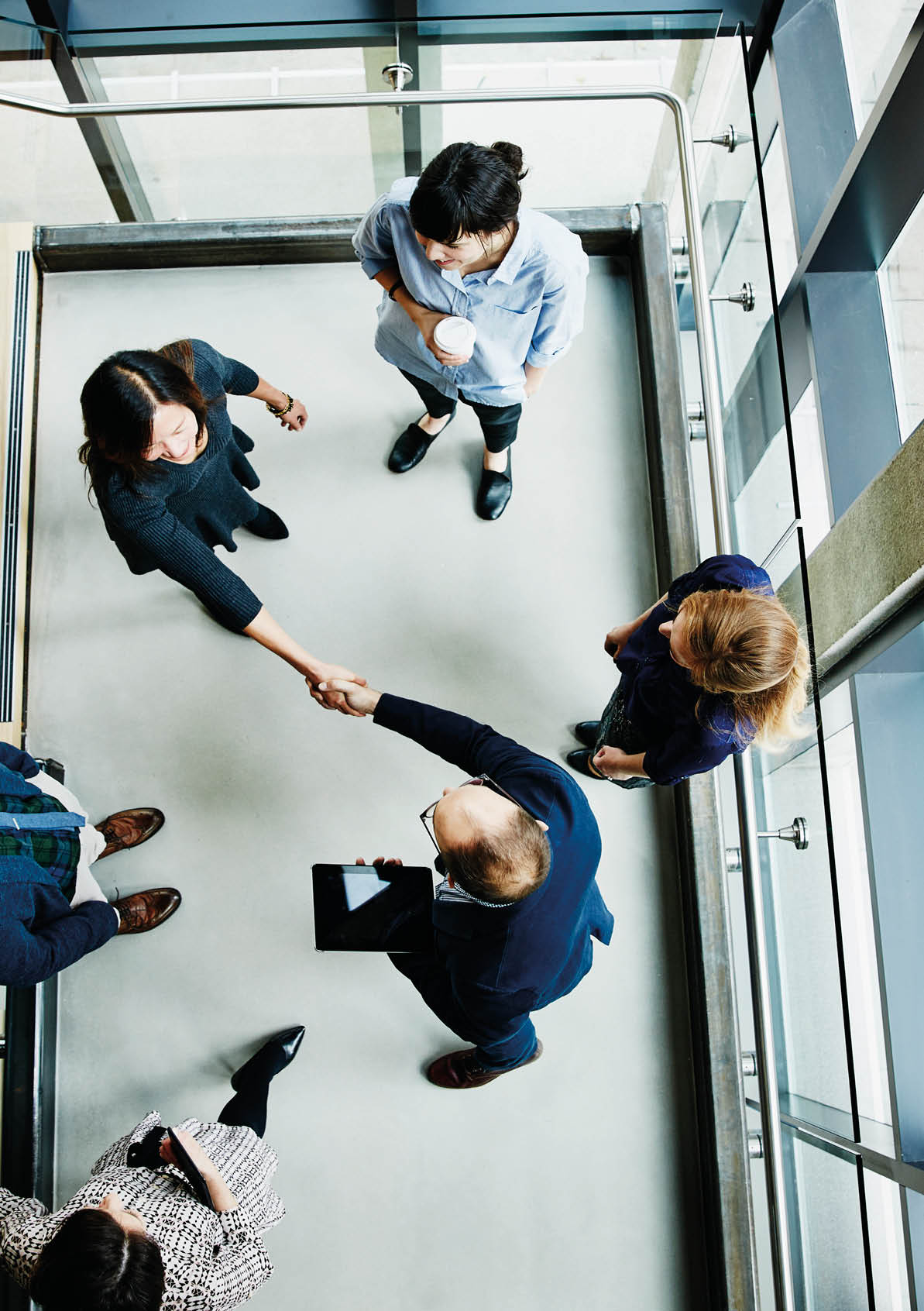 Overhead view of businesspeople shaking hands after informal meeting of office stairs