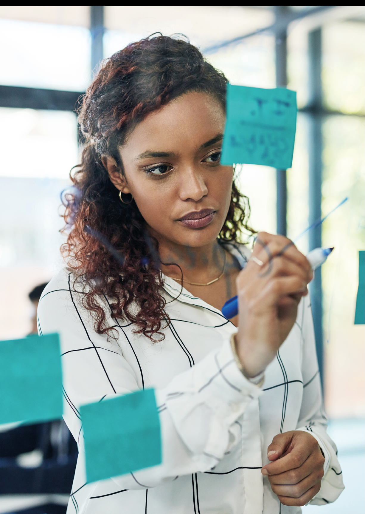Shot of a young businesswoman writing notes on a glass wall in an office
