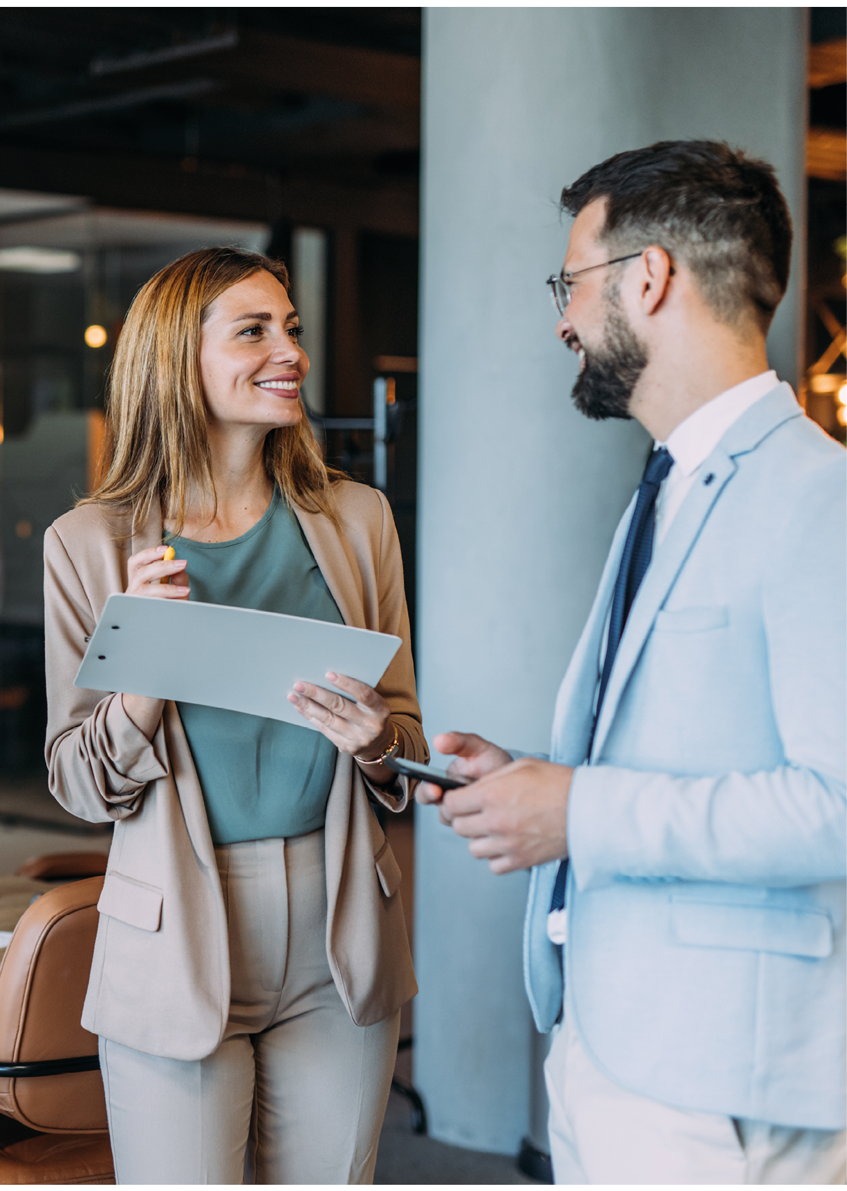 Shot of two coworkers having a discussion in modern office. Businessman and businesswoman in meeting discussing important financial documents. Confident business people working together in the office. Corporate business persons discussing new project and sharing ideas in the workplace.